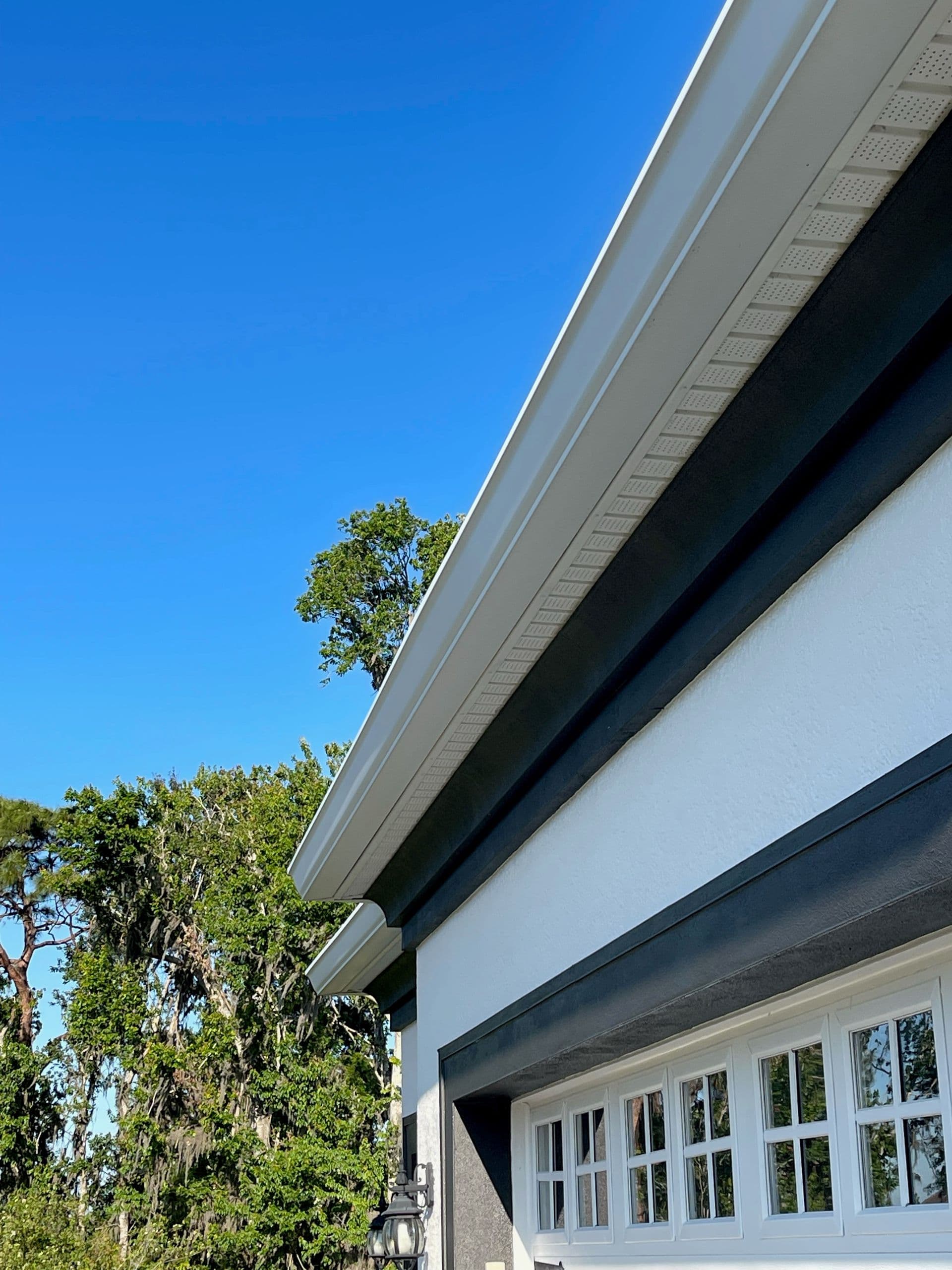 A side view of a house with new white 7-inch gutters.