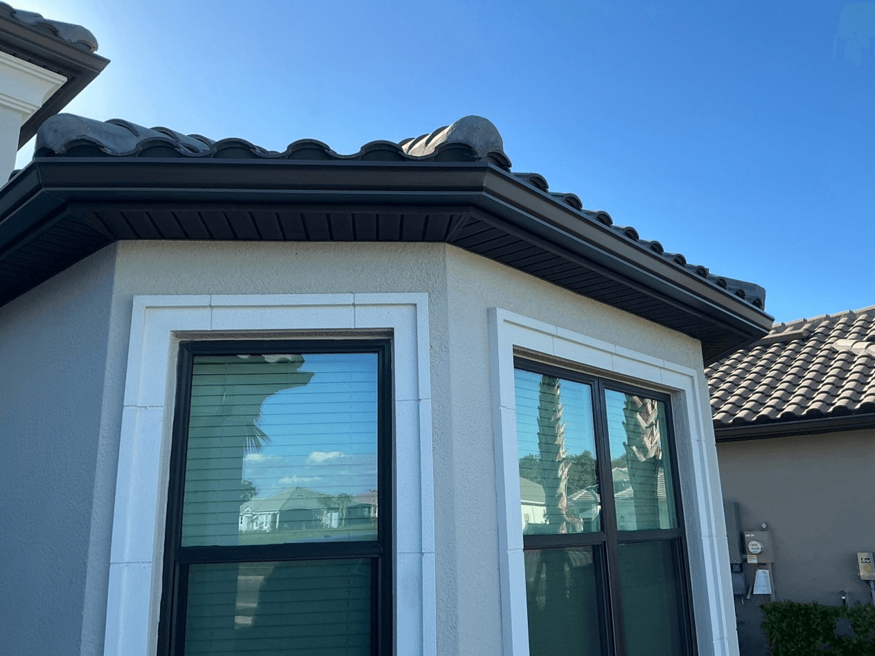 A light gray house with new black gutters.