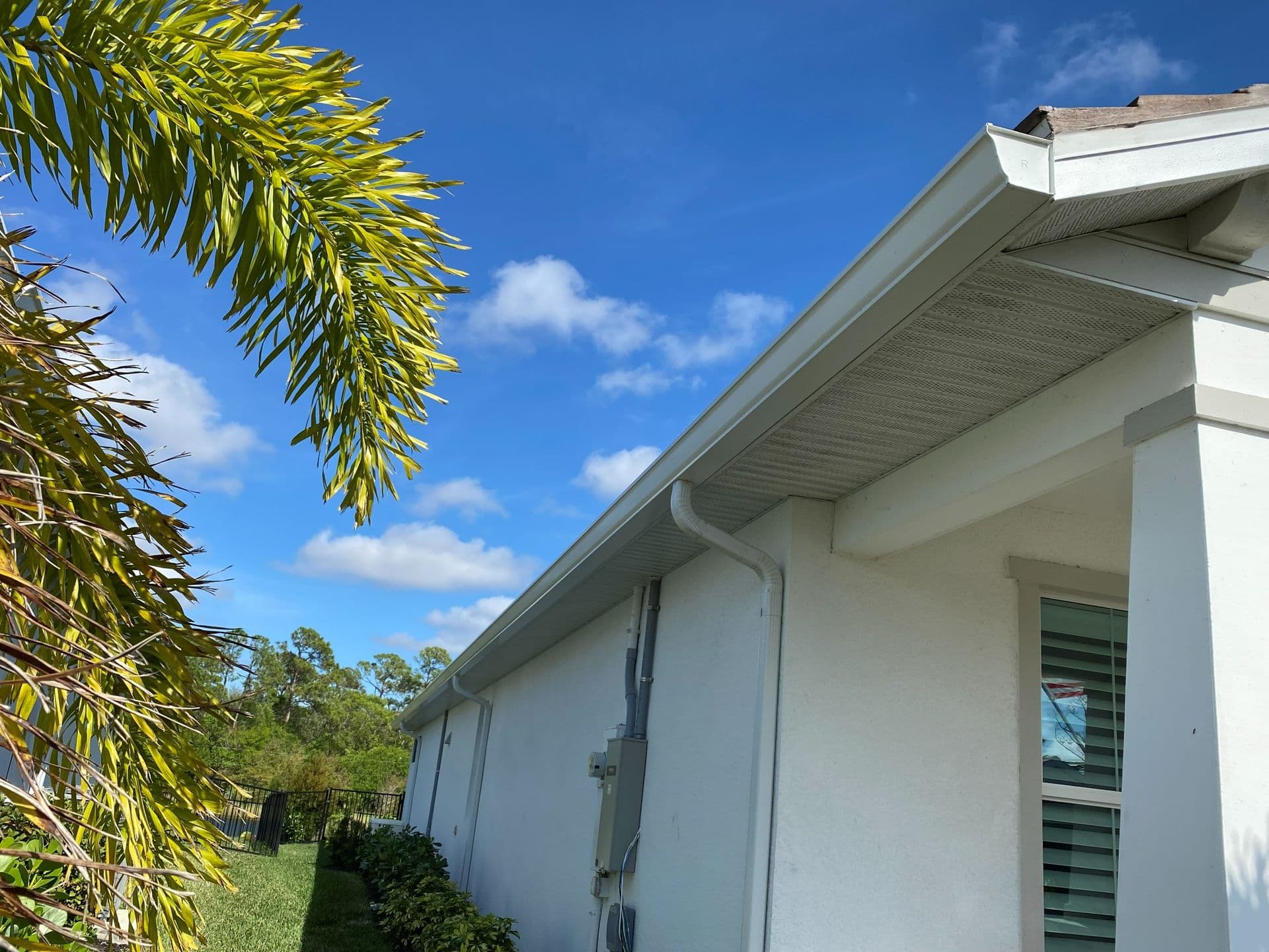 A side view of a white house with new white gutters and downspout.