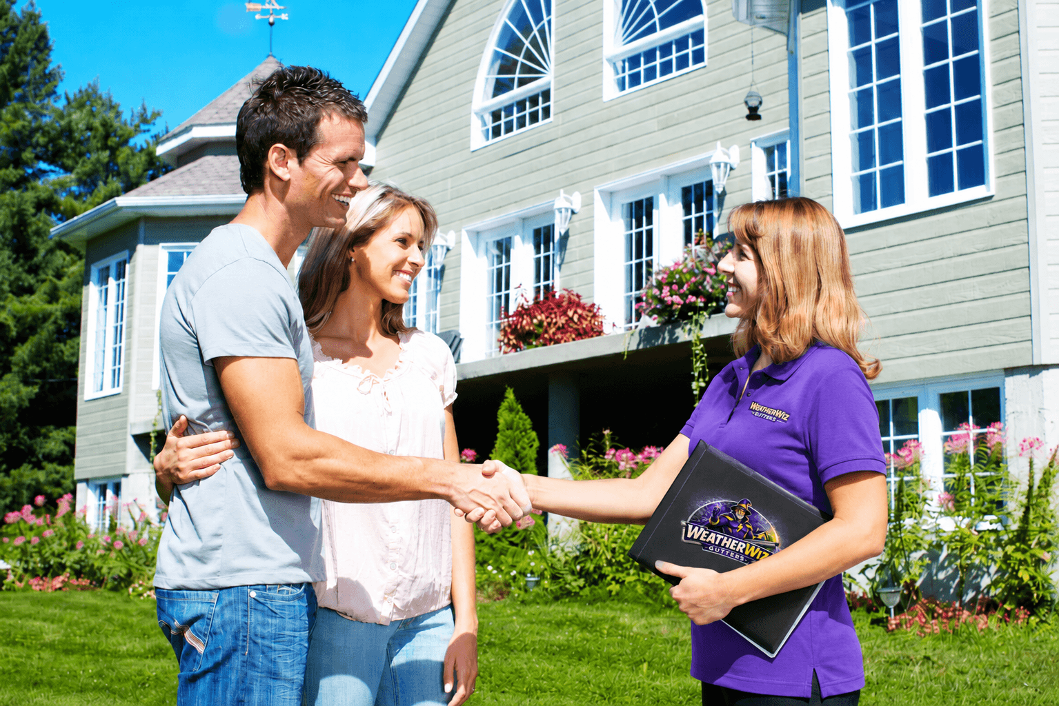 A couple shakes hands with a professional in front of a house.